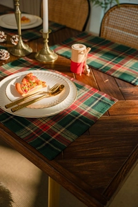 Close-up of a red and green plaid Christmas table runner with festive holiday decor