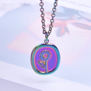 Macro shot of an iridescent stainless steel oval pendant with a sunflower engraving