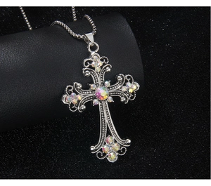 Detail of silver stainless steel cross pendant with colorful rhinestones on black stand