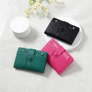 Three minimalist short leather wallets for women in black, emerald, and rose pink colors