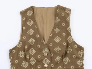 Détail de gilet marron avec broderies géométriques dorées et boutons métalliques