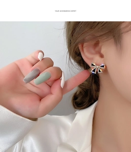 Detail of s925 black bow earrings with gold plating and sparkling rhinestones on ear