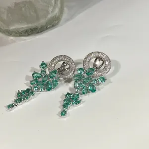 Vue détaillée de boucles d'oreilles pendantes avec pierres vertes et franges de zircon