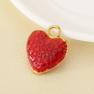 Close-up of a red enamel heart pendant with gold-plated metal edges and ring