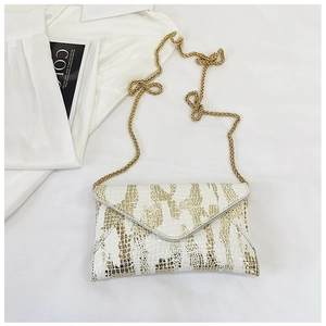 Detail showing white and gold crocodile pattern envelope bag with golden chain strap