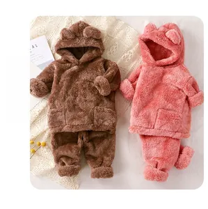 Détail à plat de pyjamas à capuche ours en peluche chaud en marron et rose poudré