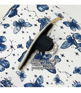 Detail of the blue butterfly print and golden zipper pocket on the white backpack