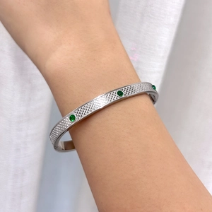 Detail of silver titanium bangle with scale texture and three green zircon stones