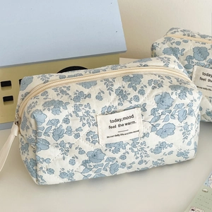Close-up of blue floral quilted cosmetic bag featuring soft texture and zipper detail