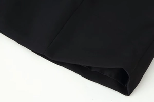 Detailed view of the stitched hem and smooth black fabric texture on the long sleeve dress