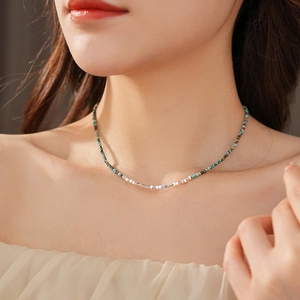 Detail of silver beads and turquoise stones necklace on model with soft lighting