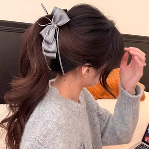 Detail of silver silk bow hair clip with central zircon accent worn on hair