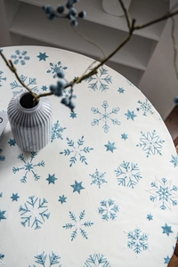 Close-up of white round tablecloth featuring blue snowflake patterns and starry prints