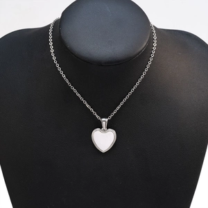 Detail of silver heart pendant with beaded edge on a black jewelry display stand