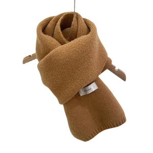 Minimalist brown knit winter scarf on wood hanger with brand label and soft texture