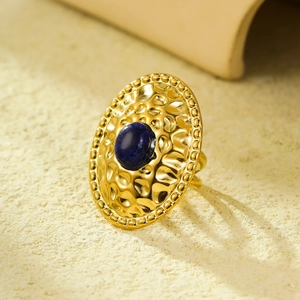Macro shot of gold hammered stainless steel ring featuring a round dark blue gemstone