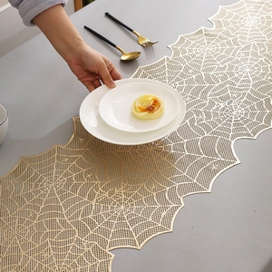 Close-up of golden hollow spider web table runner with elegant dining set on table