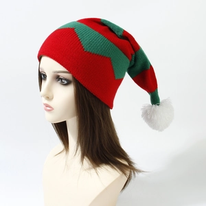 Detail of red and green zigzag knitted Christmas hat with a white fluffy pompom on top