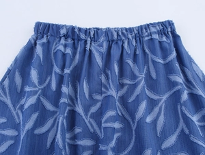 Detailed view of elastic waistband and light blue leaf-patterned jacquard denim fabric