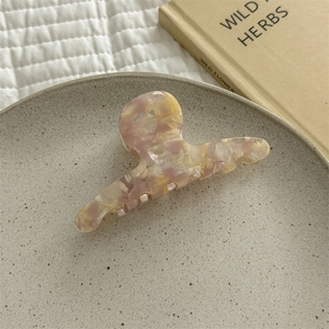 Detailed view of marble pattern acetate hair claw clip on a decorative plate