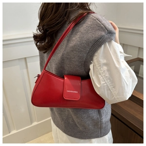 Close-up of red glossy leather shoulder bag with white lettering and matching strap