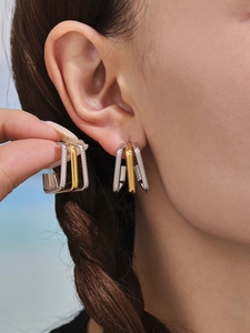 Macro detail of geometric U-shaped mixed metal earrings with dual-tone gold and silver finish
