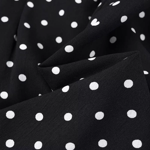 Close-up of black and white polka dot fabric texture with natural folds and soft drape