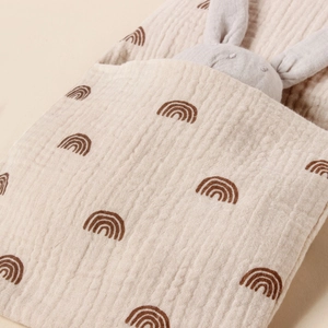 Detailed texture of cotton muslin crib organizer with rainbow print and plush bunny toy
