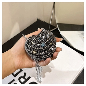 Gros plan d'un sac de soirée en forme de cœur avec strass noirs et blancs et chaîne