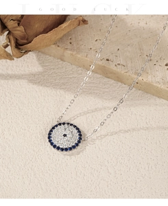 Detail shot of vintage silver Evil Eye necklace with blue gems and a dried rose background