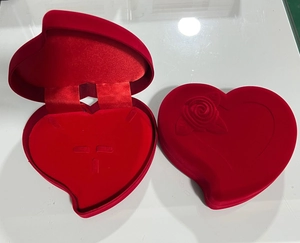 Detail of red heart-shaped velvet jewelry box featuring a 3D rose embossing on the lid