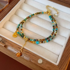 Détail du bracelet perlé avec pierres turquoise et breloques dorées en coffret cadeau