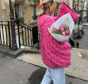 Detail of rose pink chunky knit sweater with voluminous lantern sleeves in street style