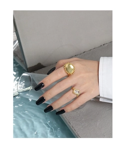 Artistic display of gold sunflower rings and rectangular diamond band on model's hand