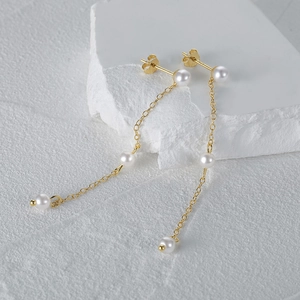 Detail of luxury S925 silver long tassel pearl earrings with gold chain on white stone