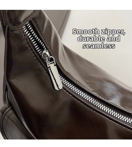Close-up of smooth silver metal zipper on premium brown glossy faux leather shoulder bag