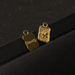 Detailed view of gold stainless steel butterfly and Beauty engraved rectangle pendants