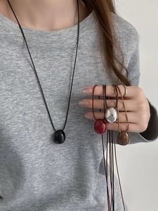 Detail shot of wax cord necklaces with oval pendants in black, red, silver, and brown