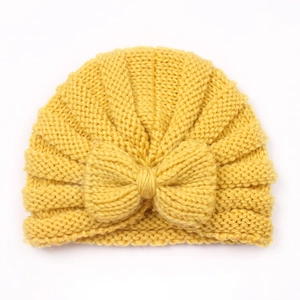 Detail of yellow knitted baby turban hat with a large decorative bow and ribbed texture