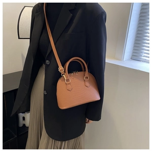 Detail of caramel embossed leather handbag featuring golden metal zipper and hardware
