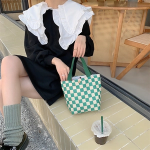 Detail of green and white checkerboard corduroy tote bag with metal buckle closure