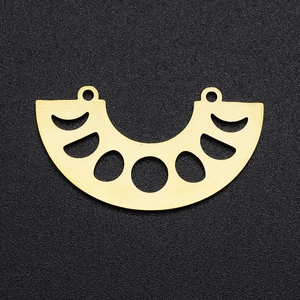 Detail of golden stainless steel hollow crescent charm with dual rings on black surface