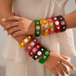 Detail of bohemian resin bangles featuring large colorful rhinestones on wrists