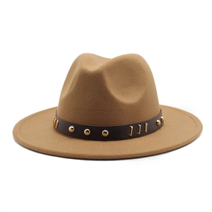 Dettaglio di cappello in lana color cammello con fascia in pelle e borchie dorate