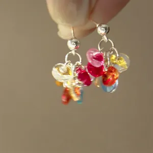 Macro detail of S925 silver hook earrings with colorful transparent resin floral beads