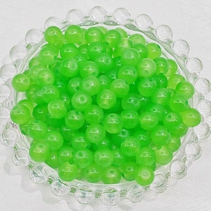 Close-up of grass green round glass beads in a clear tray for DIY jewelry making