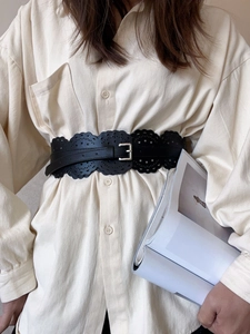 Détail de la ceinture large noire ajourée avec boucle en métal argenté sur chemise