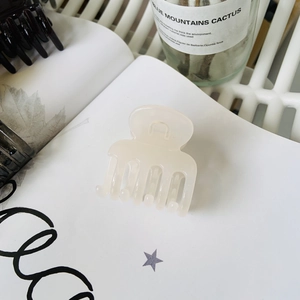 Close-up of a cream translucent hair claw clip on aesthetic paper with soft lighting