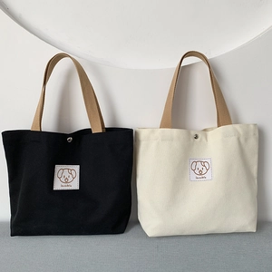 Close-up of small canvas tote bags in black and beige with durable brown ribbon handles