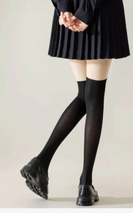 Gros plan de chaussettes hautes Lolita noires avec jupe plissée et mocassins